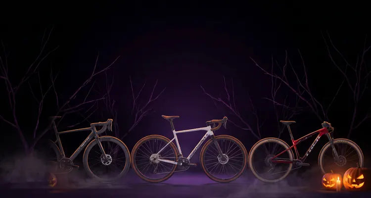 Tre biciclette in uno studio buio con zucche di Halloween